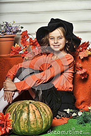 Girl in an orange sweater and hat in Halloween witch