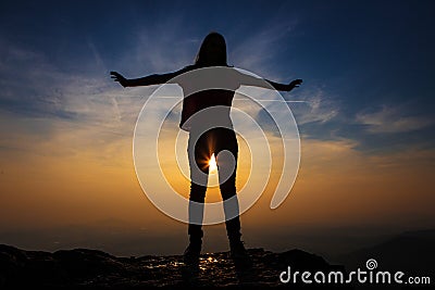 Girl with outstretched hands at sunset silhouette