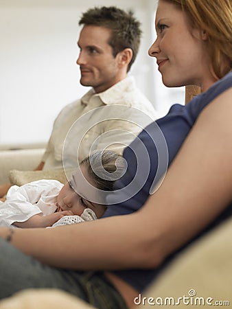 Girl And Parents Watching TV At Home