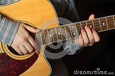 Girl playing an acoustic guitar closeup