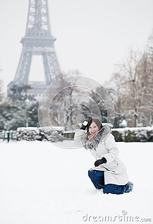 Girl playing snowballs near the Eiffel tower in Paris