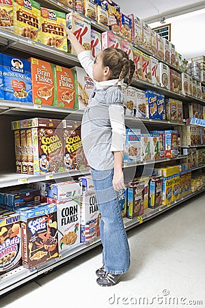 Girl Reaching For Cereal Product In Supermarket