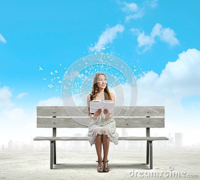 Asian pretty woman sitting on bench and reading book.