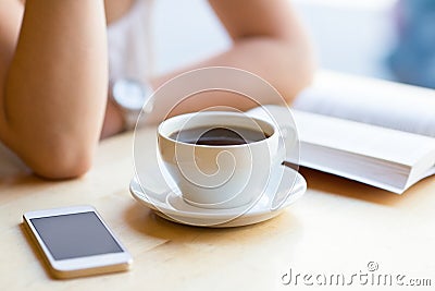 Girl reading book and drinking coffee at cafe