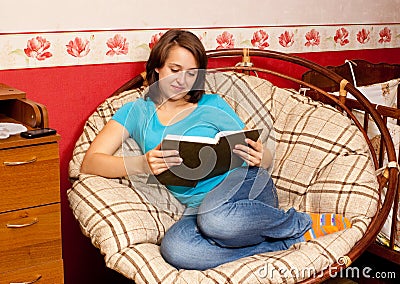 The girl reads the book in an armchair