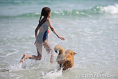 Girl runs with a dog through the water