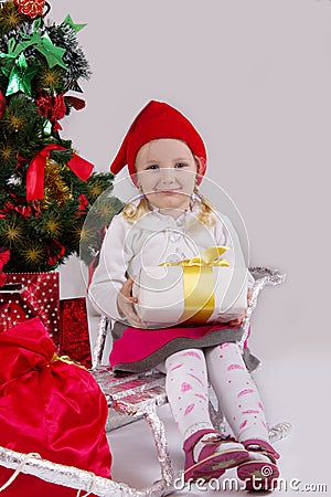 Girl in Santa hat with present on sledge