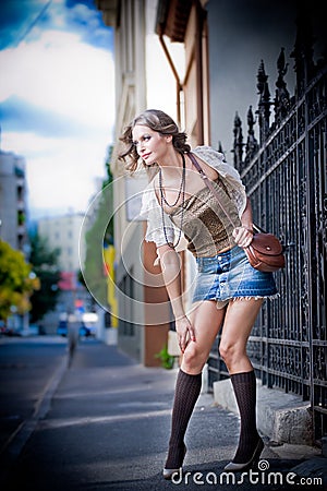Girl short skirt and bag walking on street.Young European Girl in Urban Setting