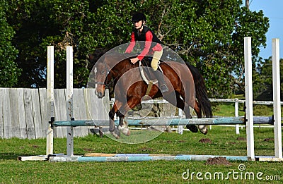 Girl show jumping with pony