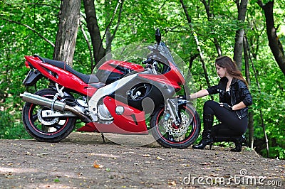 The girl sit and talk with sports bike in the woods