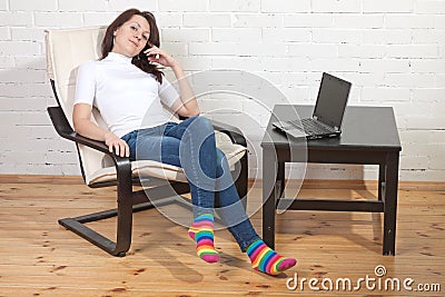 Girl sits on a armchair and works with notebook