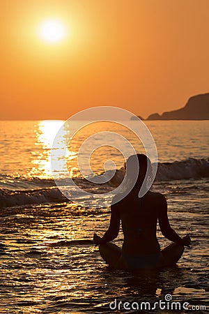 Girl sitting in a yoga pose on the beach