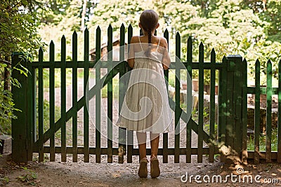 Girl standing on tiptoes and looking over the fence
