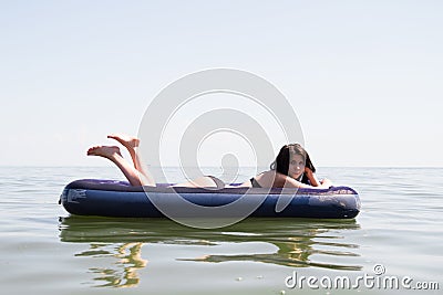 Girl sunbathing on air mattress in sea