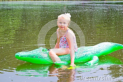 Girl swimming in the river with inflatable crocodile