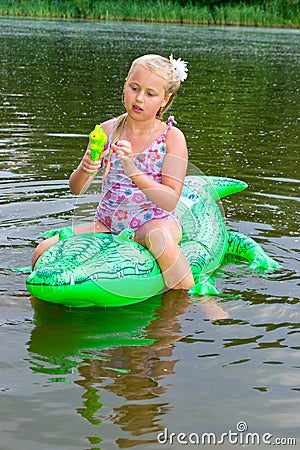 Girl swimming in the river with inflatable crocodile