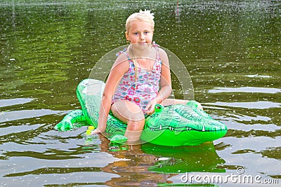 Girl swimming in the river with inflatable crocodile