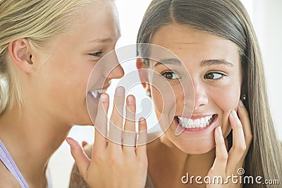 Girl Whispering Into Friend s Ear