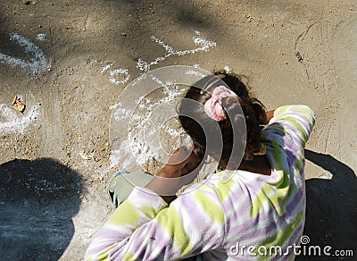 Girl writing graffiti with white chalk on the ground in a camping trip in Egypt
