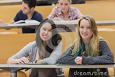 Girls smiling in lecture hall with tablet pc