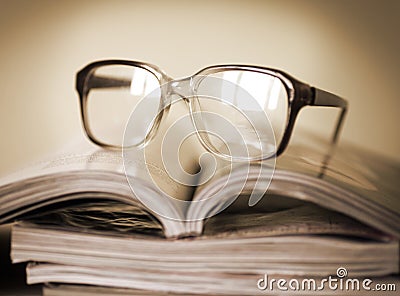 Glasses for reading on a stack of magazines, in soft focus