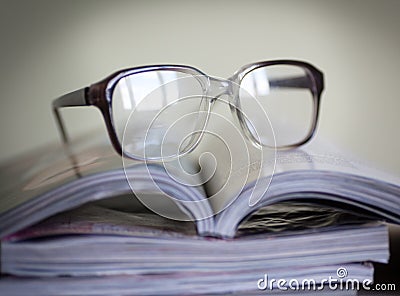 Glasses for reading on a stack of magazines, in soft focus