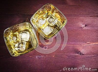 Glasses of whiskey with ice on wood table