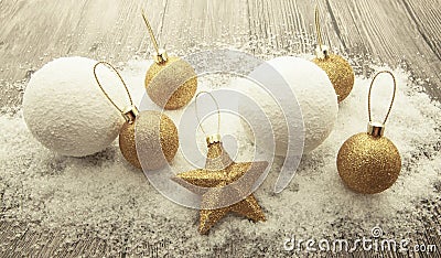 Glittering gold Christmas balls, snowballs, winter snow and star on wooden background