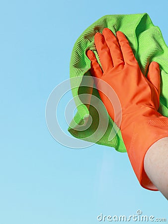 Gloved hand cleaning window with rag