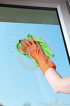 Gloved hand cleaning window with rag