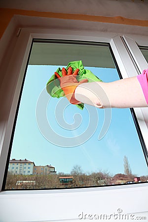 Gloved hand cleaning window with rag