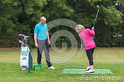 Golf pro assessing a lady golfers backswing