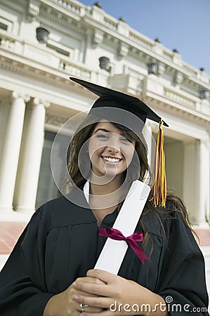 Graduate holding diploma outside university portrait