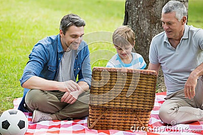 Grandfather father and son with picnic basket at park