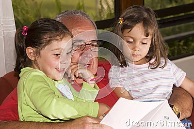 Grandfather and granddaughters reading together