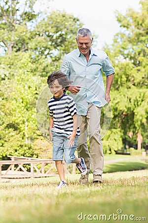 Grandfather and son running on grass in park