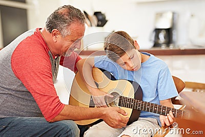 Grandfather Teaching Grandson To Play Guitar