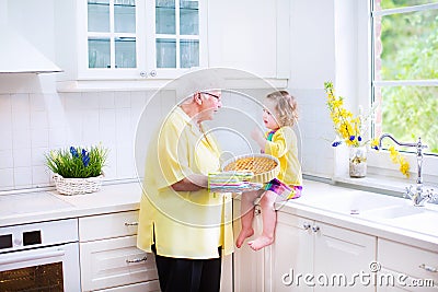 Grandmother and funny girl baking pie in white kitchen