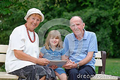 Grandmother, grandfather and granddaughter using tablet