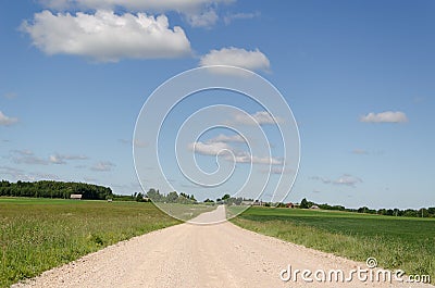 Gravel road continues along fields and blue sky