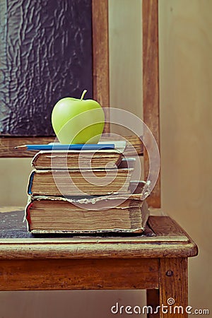 Green apple and old books on an old chair with vintage feel