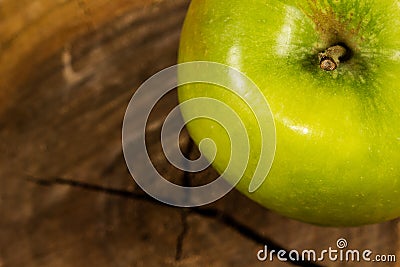 Green apple on a piece of wood cut