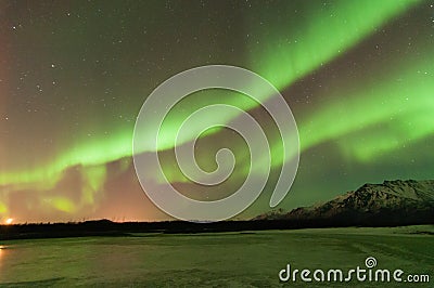 Green Aurora Over Mountains And A Frozen Lake