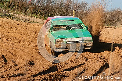 The green car lifts sandy splashes