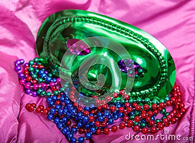 Green Mask and Mardi Gras Beads on Purple Background