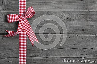 Grey wooden background with red and white checkered bow as borde