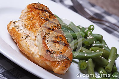Grilled chicken meat with green beans on a white plate