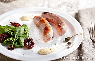 Grilled sausages with salad on a white plate