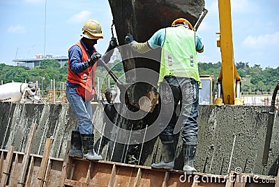 Group of construction workers casting concrete wall