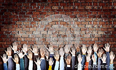 Group of Diverse Hands Raised on Brick Wall